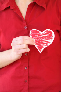Woman holding paper heart cutout over chest